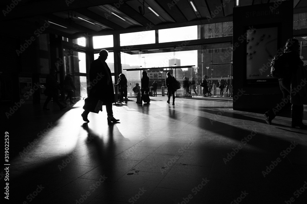 Silhouette of a man carrying a portfolio that runs through a light window of a train station