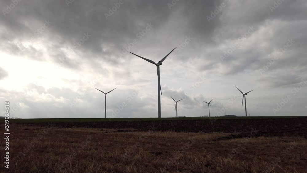 Groupe d'éoliennes en contre jour durant un coucher de soleil dans un champs - Parc éolien à fort impact visuel Groupe d'éoliennes en contre jour durant un coucher de soleil dans un champs - Parc éolien à fort impact visuel