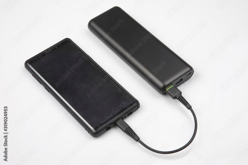 powerbank charges a smartphone battery on a white background. digital technologies and devices powerbank charges a smartphone battery on a white background. digital technologies and devices