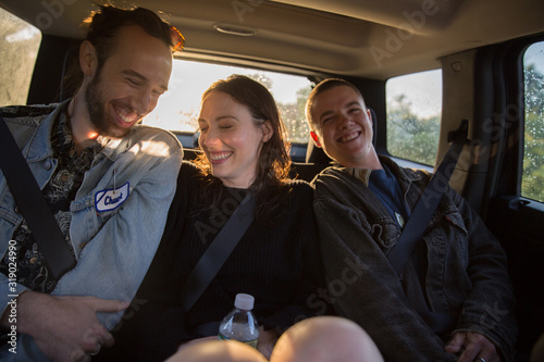 Three young adults sitting in the backseat of a car on roadtrip in summertime, laughing, hip, millennials, androgynous, gender neutral, ethnically ambiguous