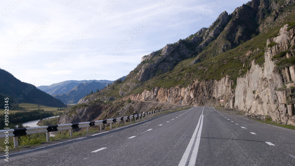 Naklejka premium Beautiful smooth asphalt road in the mountains. Marking on a country road. It's a lonely road without cars