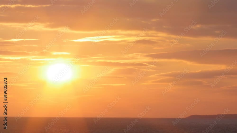 beautiful sunset on the background of sea, sun going beyond the horizon illuminating water and clouds in the sky beautiful sunset on the background of sea, sun going beyond the horizon illuminating water and clouds in the sky