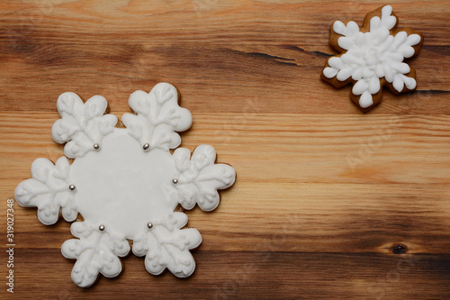 Two gingerbread cookies in the shape of snowflakes on a wooden Board