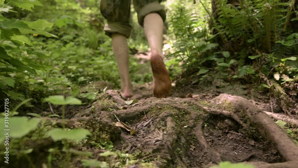 Closeup. Legs of a man. Traveler goes barefoot on rocky road, climbs up by river Closeup. Legs of a man. Traveler goes barefoot on rocky road, climbs up by river