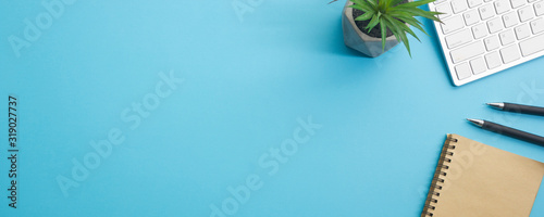 Blue desk office with laptop, smartphone and other work supplies with cup of coffee. Top view with copy space for input the text. Designer workspace on desk table essential elements on flat lay
