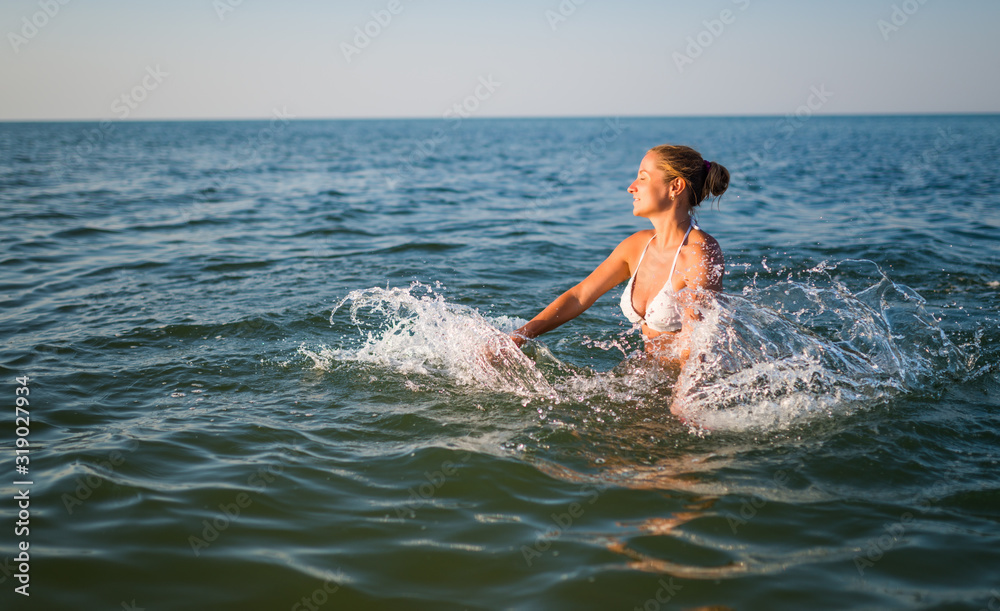 Rear view of a pretty young woman swimming in the sea on a sunny warm summer day. The concept of rest and enjoyment of tourist trips. Copyspace