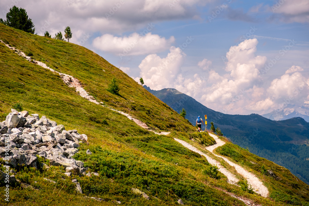 Φωτογραφία Back view of a hiker with backpack on gravel hiking trail high up in the Swiss Alps above the alpine village of Saint-Luc in the Val d' Anniviers in summer