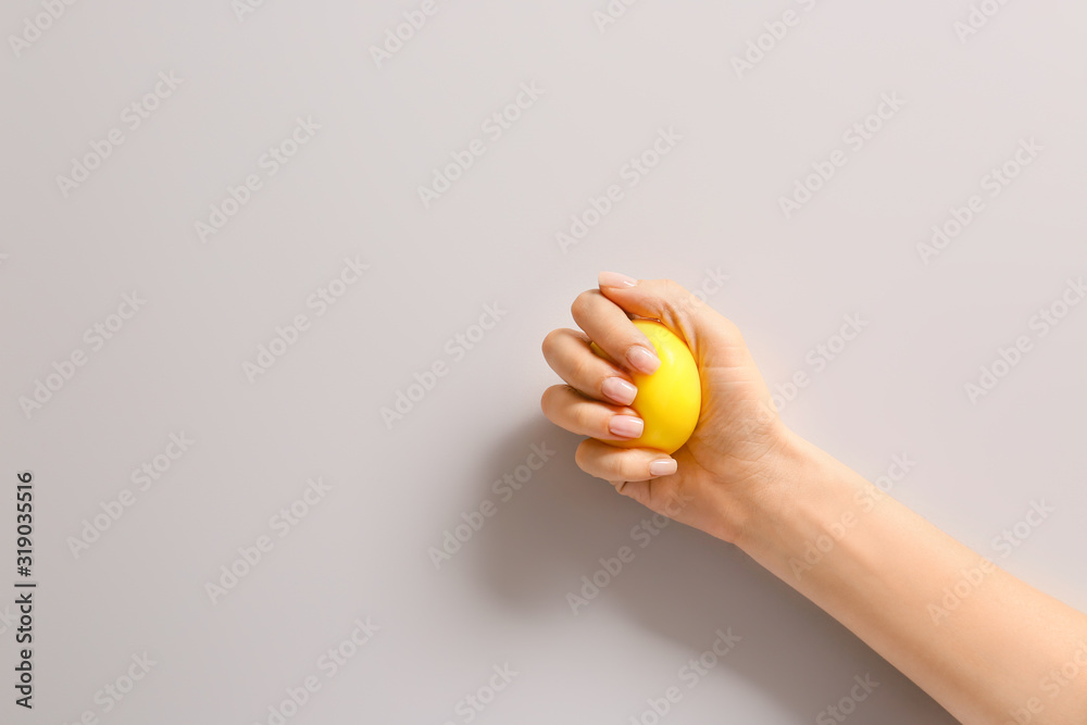 Hand squeezing stress ball on light background - obrazy, fototapety, plakaty 