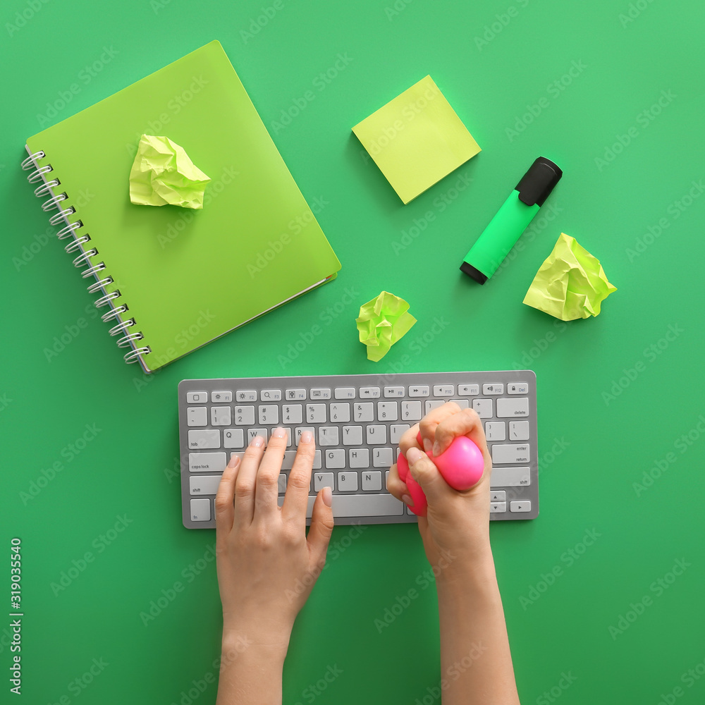 Woman squeezing stress ball while working on PC, top view Woman squeezing stress ball while working on PC, top view