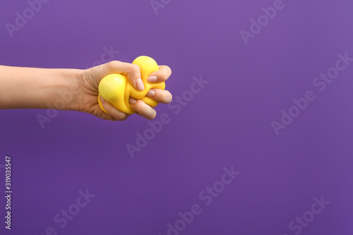 Hand squeezing stress ball on color background