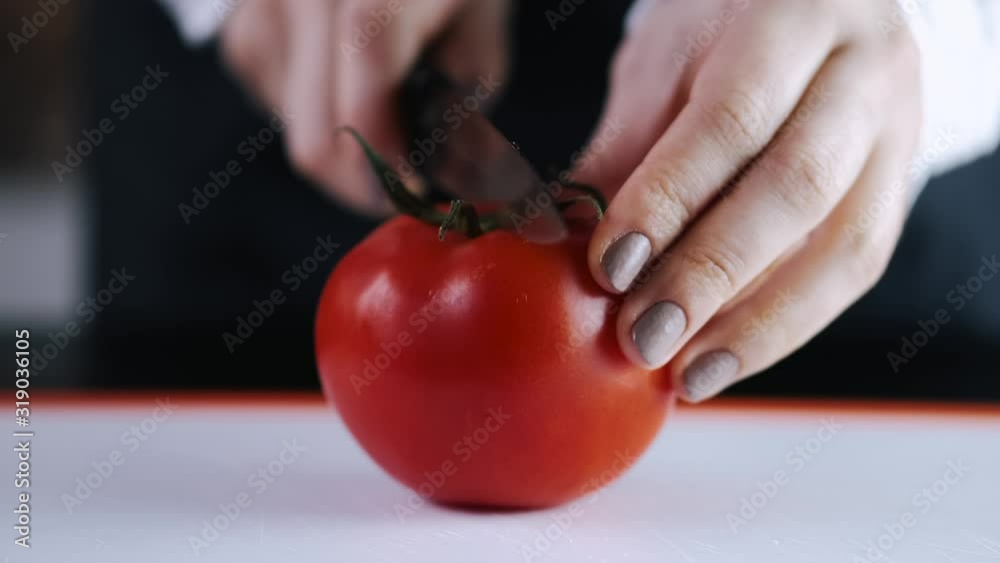 A fresh tomato is being cut with a knife. A fresh tomato is being cut with a knife.