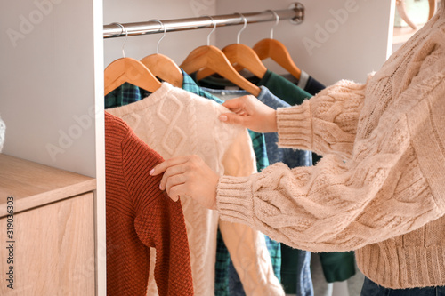 Woman choosing winter clothes near wardrobe photo