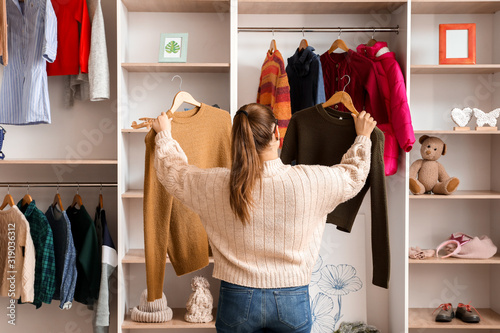 Canvastavla Woman choosing winter clothes near wardrobe