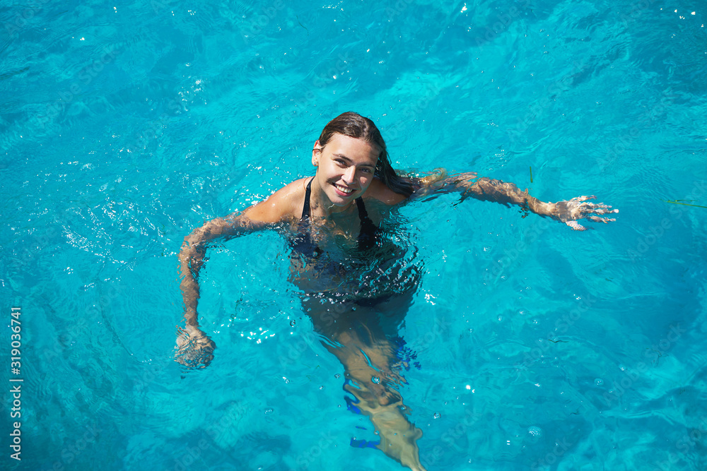 Happy beautiful woman is swimming in turquoise sea on summer holidays.