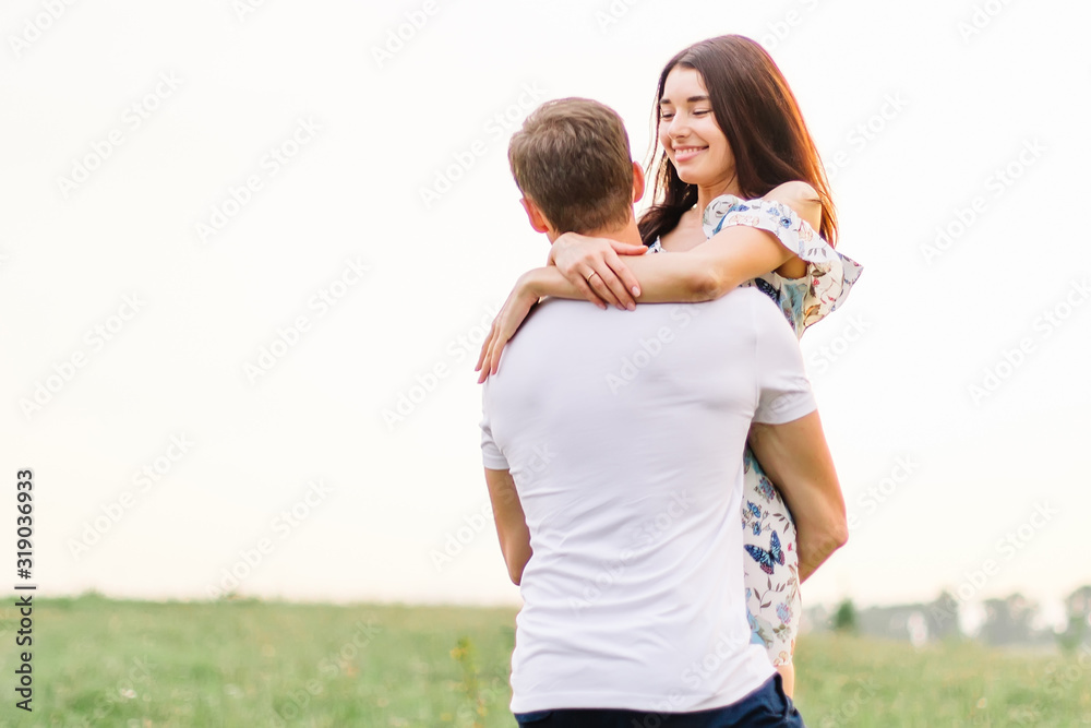 Young couple in love hugging on grass field. Walking along grass field.