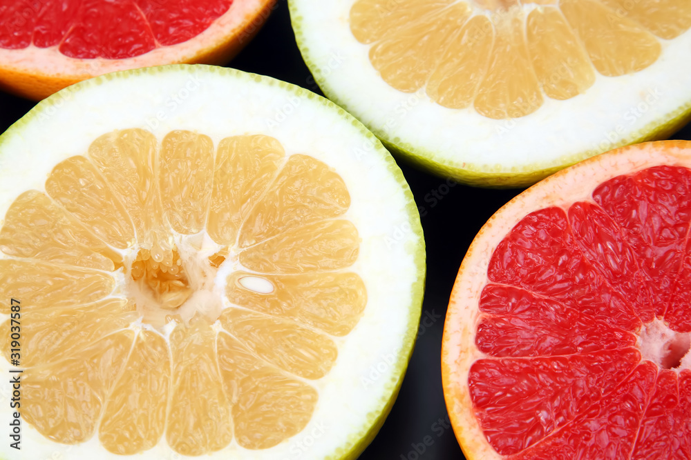cut pieces of different citrus fruits on dark background cut pieces of different citrus fruits on dark background