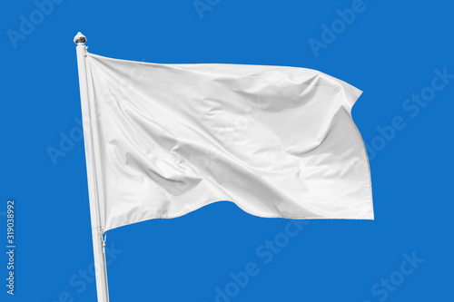 White flag waving in the wind on flagpole, isolated on blue background, closeup photo