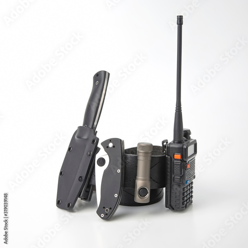 the folding knife, radio transmitter a flashlight on a black leather strapthe Fototapet