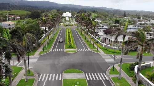 Aerial view flying over a street between palms heading towards a temple in Oahu, Hawaii