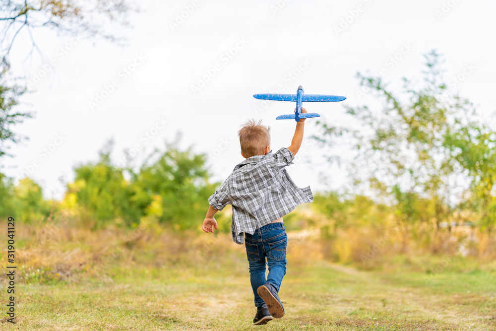 Young boy play with toy airplaine in hands. Happy Kid is playing in park outdoors. Young boy play with toy airplaine in hands. Happy Kid is playing in park outdoors.