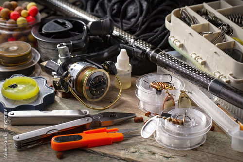 Fishing rods and spinnings in the composition with accessories for fishing on the old background on the table