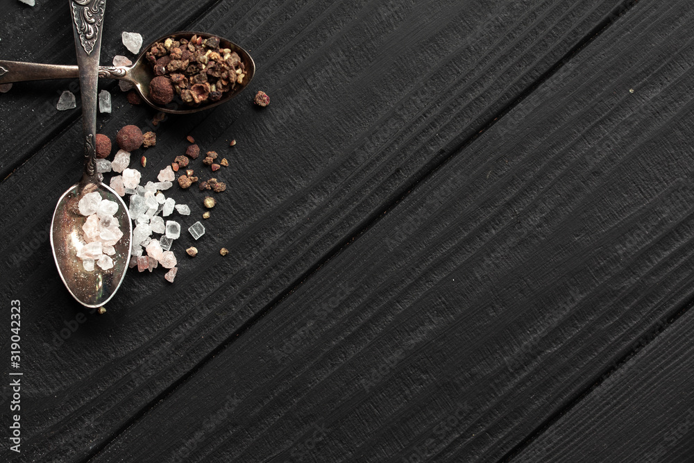 Spoons with Himalayan salt and seasonings on a black wooden background with a slate under the inscription Spoons with Himalayan salt and seasonings on a black wooden background with a slate under the inscription