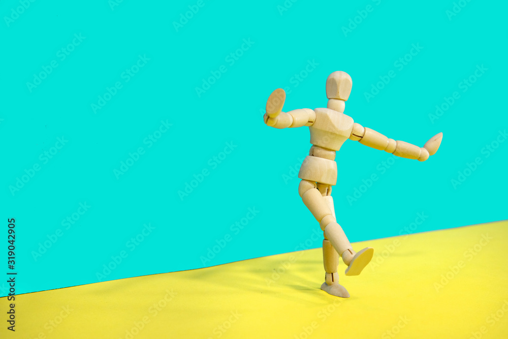 Wooden mannequin posing over yellow and green background
