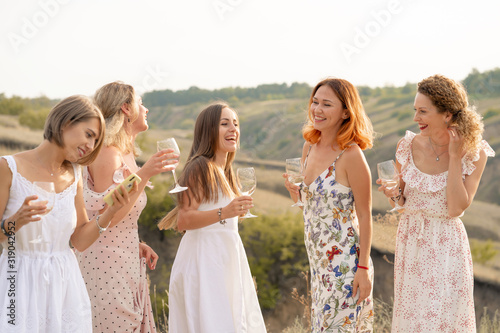 The company of gorgeous female friends having fun and enjoys a summer green hlls picnic, dancing and drink alcohol. People concept.