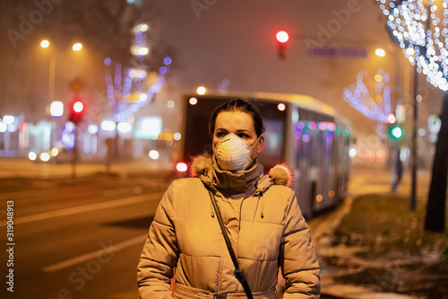 Young woman wearing mask to protect her from viruses, smog, exhaust fumes and other atmospheric pollutants in thick fog. Conceptual photo about health, ecology and air pollution.