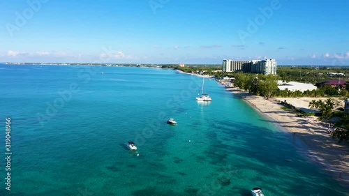 aerial drone footage of seven mile beach, west bay and george town on the island of grand cayman in the cayman islands in the clear blue and green tropical waters of the caribbean sea