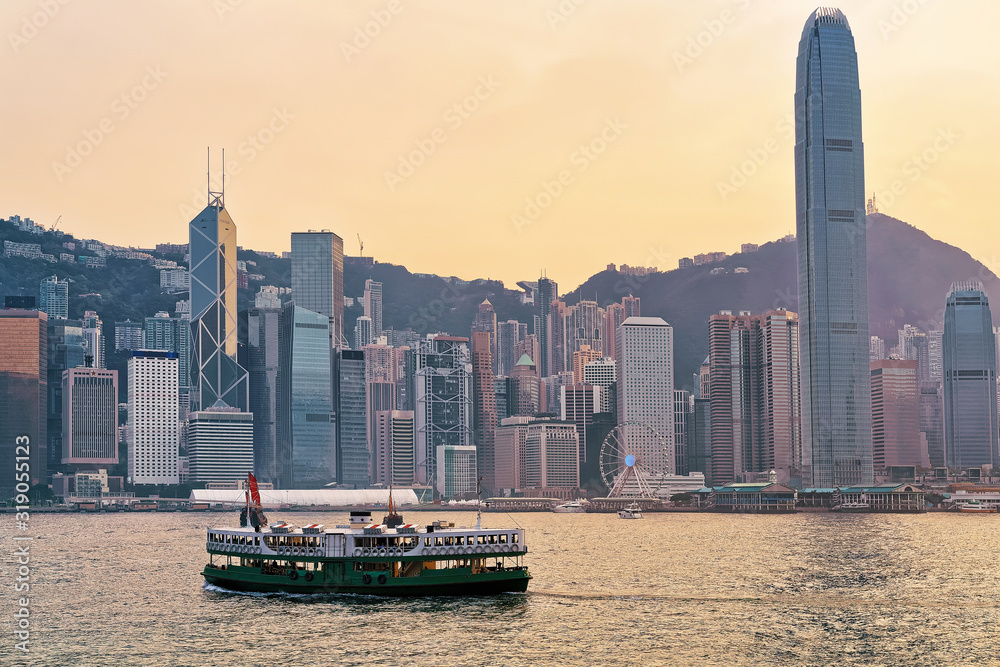 Fototapeta premium Star ferry at Victoria Harbor of HK at sundown. View from Kowloon on Hong Kong Island.