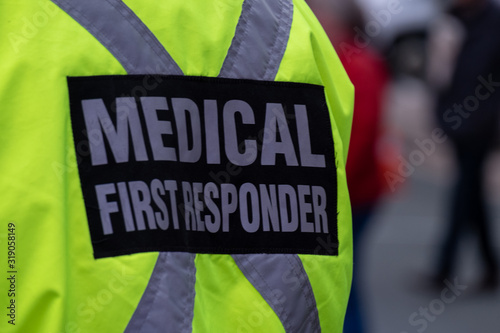 Medical First Responder wearing a bright yellow jacket with a reflective material in across on the person's back.  Medical first responder wearing a bright yellow coat with a grey reflective cross.