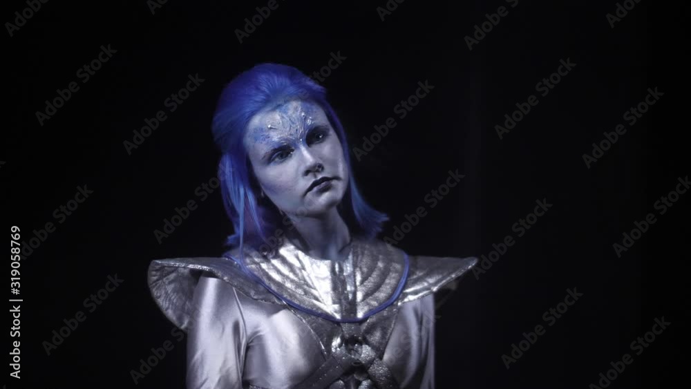 Alien with blue hair is standing and looking somewhere Alien with blue hair is standing and looking somewhere