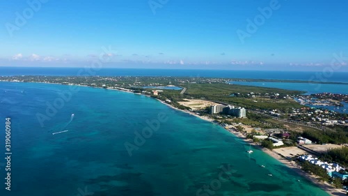 aerial drone footage of seven mile beach, west bay and george town on the island of grand cayman in the cayman islands in the clear blue and green tropical waters of the caribbean sea