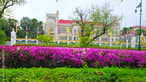 BANGKOK, THAILAND - MAY 13, 2019: The facade of Thai-Khu-Fah palace of Government House through the lush greenery and bougainvillea flowers around the Khlong Prem Prachakon canal, on May 13 in Bangkok photo