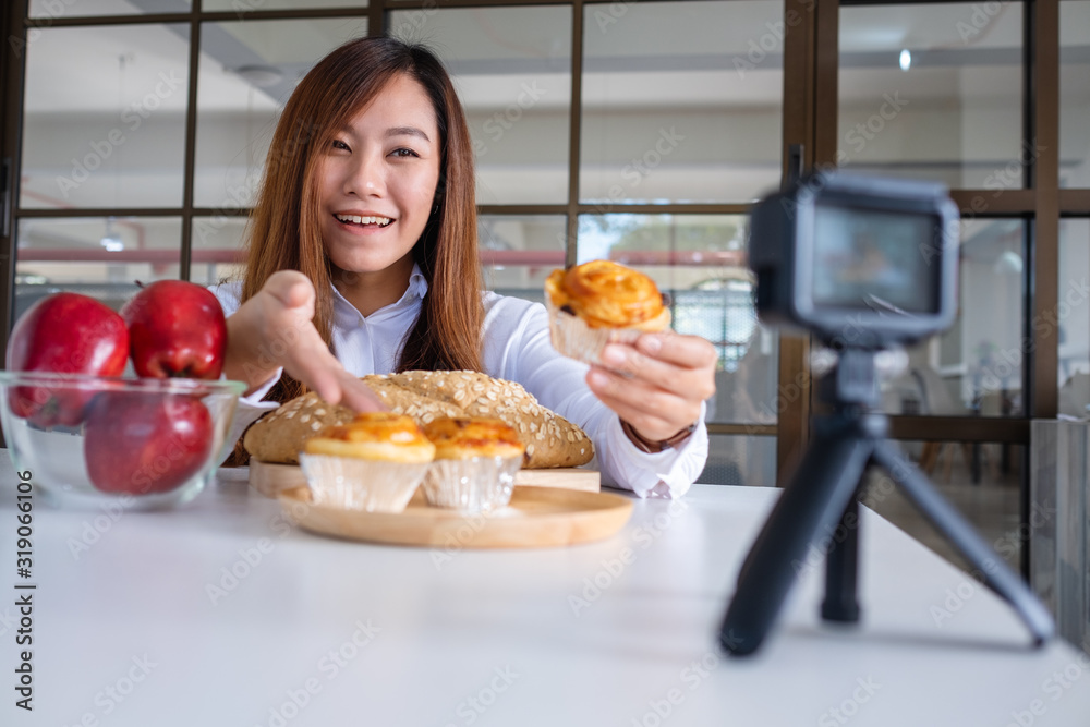 A beautiful asian woman food blogger or vlogger recording a video on camera A beautiful asian woman food blogger or vlogger recording a video on camera