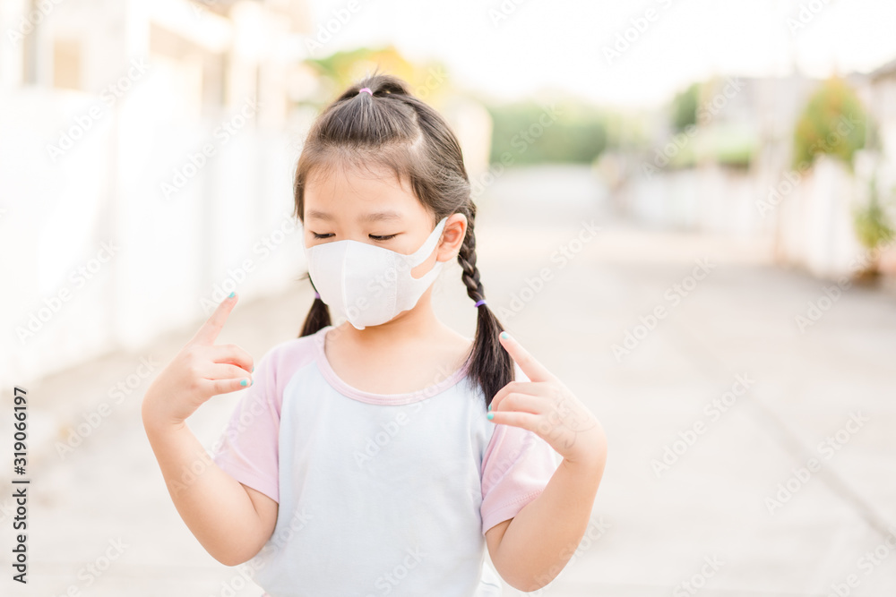Coronavirus and Air pollution pm2.5 concept.Little chinese girl wearing mask for protect pm2.5 and pointing finger in mask for corona virus protection.Wuhan coronavirus and epidemic virus symptoms. Coronavirus and Air pollution pm2.5 concept.Little chinese girl wearing mask for protect pm2.5 and pointing finger in mask for corona virus protection.Wuhan coronavirus and epidemic virus symptoms.