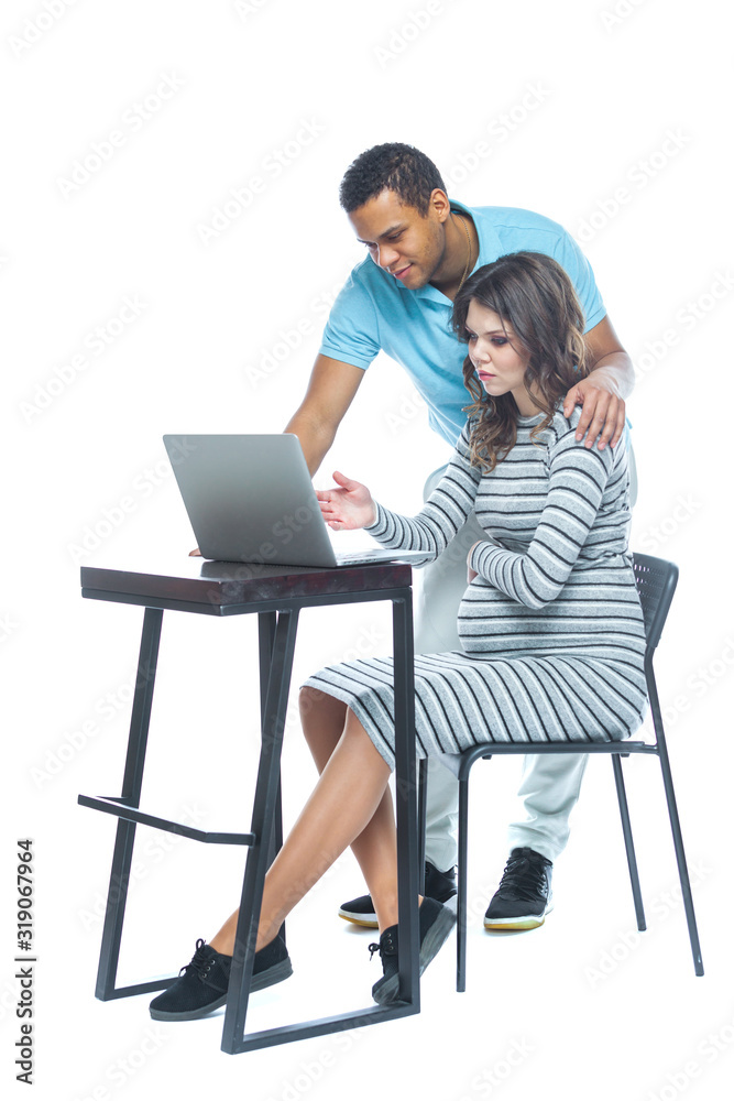 Portrait of a lovely young pregnant couple sitting on a couch with laptop computer. Black man and white woman. Portrait of a lovely young pregnant couple sitting on a couch with laptop computer. Black man and white woman.