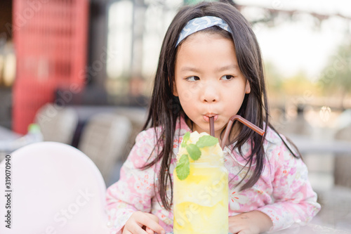 Little asian girl drinking fresh Pineapple and Passion fruit smoothie in breakfast time.Healthy drink, Super food, Vacation summer, Summer drink concept.