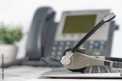 Phone and headphones on a laptop, work in a call center, support service on a light office background
