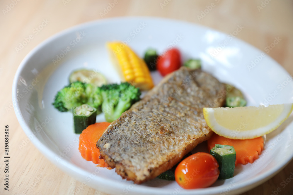 Sea bass fillet , baked sea bass with lemon sauce on wood background Sea bass fillet , baked sea bass with lemon sauce on wood background