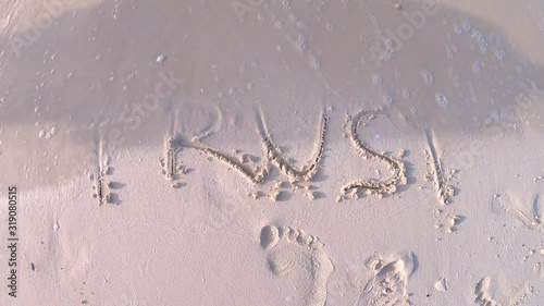 The word TRUST drawn on a sandy beach being washed out by sea waves. Concept of losing trust. photo