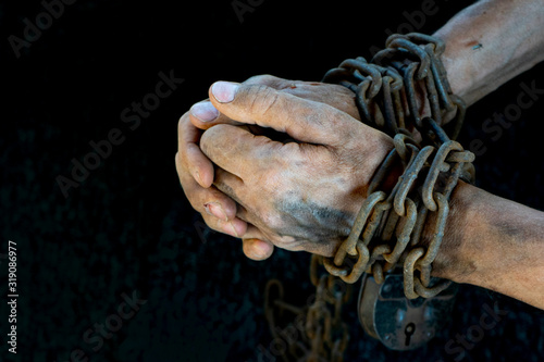 Hands of a humble slave who is not trying to free himself against a dark background