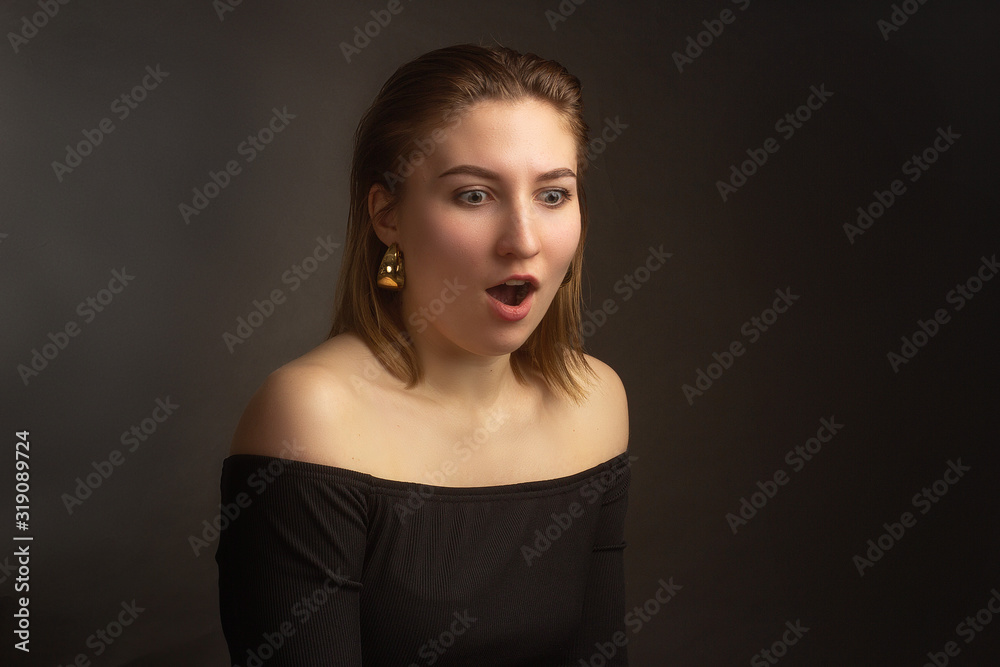 Portrait in the photo Studio of a brown-haired girl, on a black background in black clothes with open shoulders. Short hair. Portrait in the photo Studio of a brown-haired girl, on a black background in black clothes with open shoulders. Short hair.