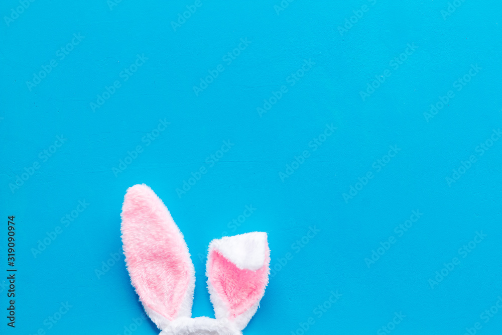 Easter bunny concept. Toy rabbit's ears on blue background top-down copy space