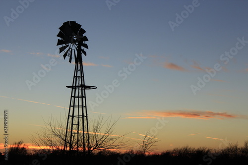 windmill at sunset with tree silhouettes north of Hutchinson Kansas USA.