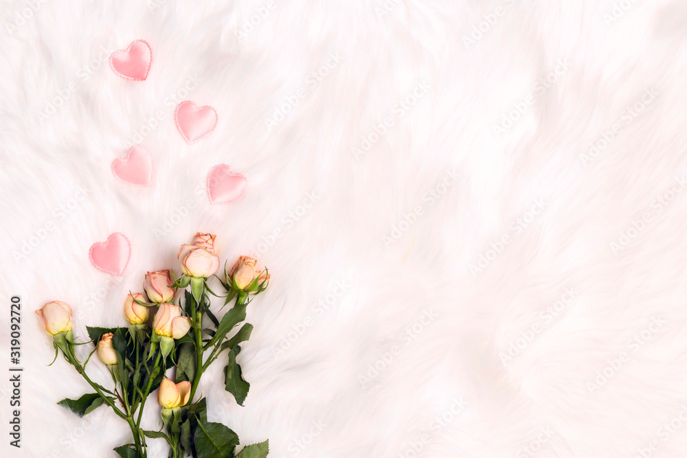 A bouquet of small roses with pink hearts on white fur background. Place for text, top down composition.