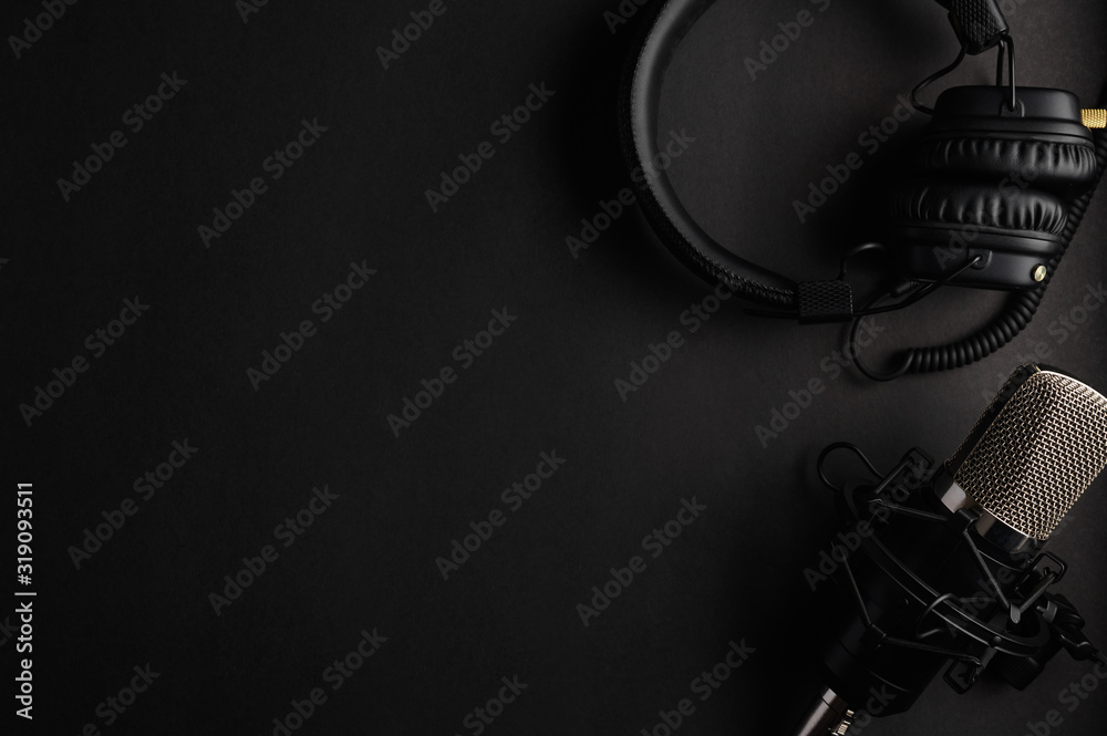 Studio black studio microphone with studio headphones on a black background. Banner. Radio, work with sound, podcasts.