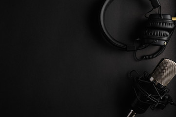 Studio black studio microphone with studio headphones on a black background. Banner. Radio, work with sound, podcasts.
