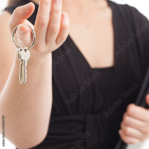 Female real estate sales or leasing agent holding keys in fingers.